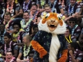 Mascot Randy Westmoreland performs a dance as the varsity football team, decked out in leis and Hawaiian wear, laughs and cheers.